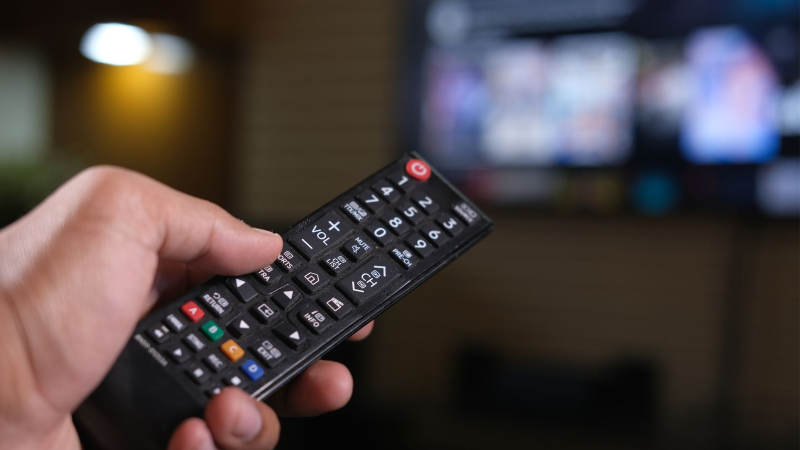 Mando a distancia de televisor Samsung apuntando hacia una pantalla de TV encendida en sala de estar